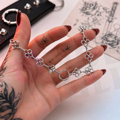 Wonder Skull Flower Link O-Ring Day Collar A quiet promise of devotion. This day collar features delicate stainless steel blossoms meeting at a polished 1.6 cm O-ring. Waterproof, tarnish-resistant, and built for 24/7 wear, it is available in 16" or 18" lengths. It is subtle enough to pass as everyday jewelry, yet unmistakable to those in the know. Pretty on the surface, unbreakable underneath.