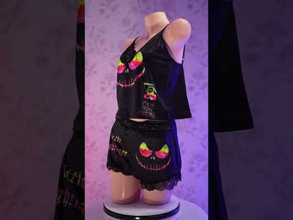 Transform your nighttime routine with the Wonder Skull glow-in-the-dark sleepwear set. The vibrant rainbow skull graphics absorb light by day and glow when darkness falls. Made from a buttery-soft, breathable fabric, this set keeps you cool all night. The delicate, dotted lace trim adds a feminine touch without being scratchy, while adjustable spaghetti straps ensure a perfect fit. This three-piece set includes a matching cami, shorts, and thong, letting you express your bold personality in comfort.